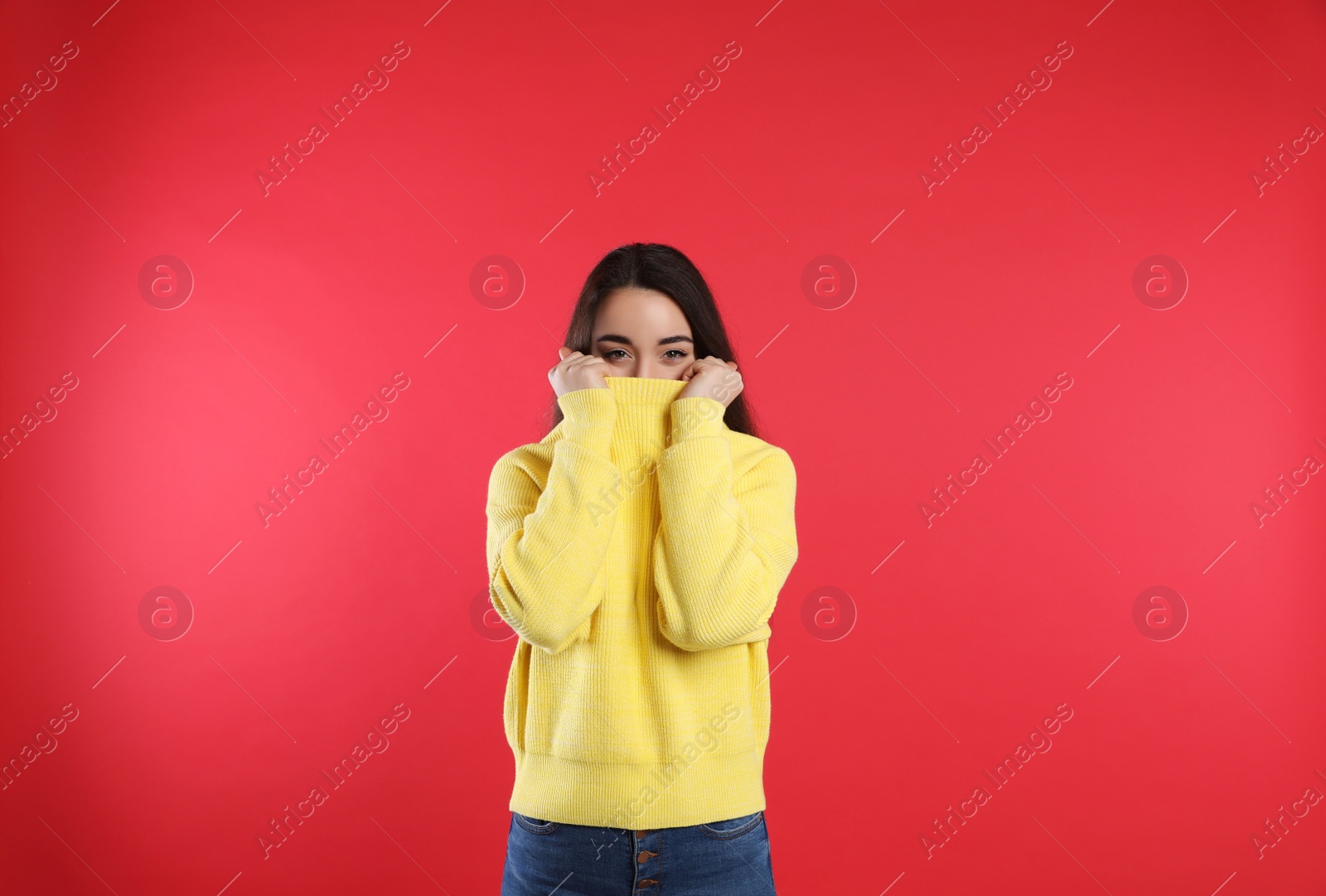 Photo of Beautiful young woman wearing yellow warm sweater on red background