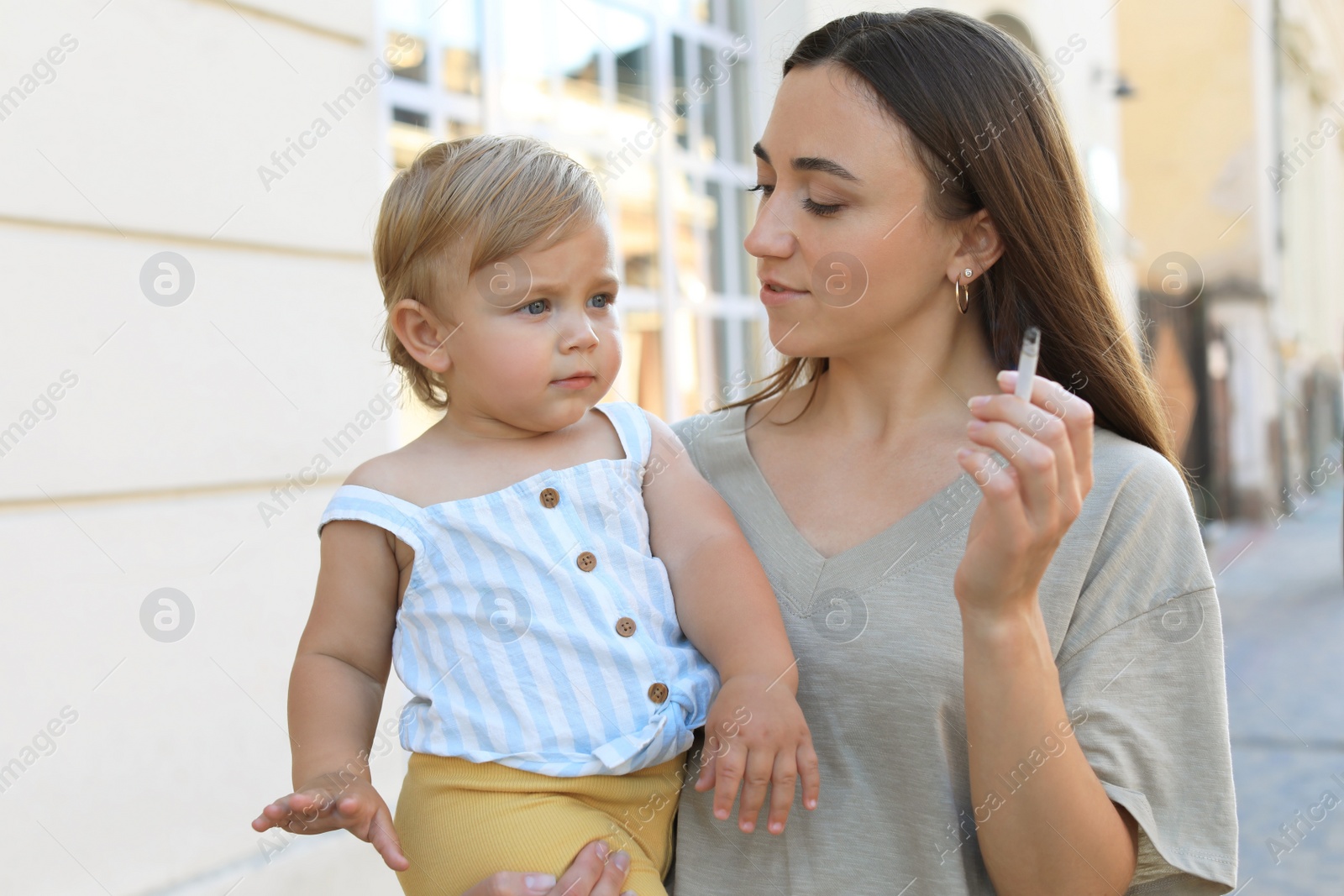 Photo of Mother with cigarette and child outdoors. Don't smoke near kids