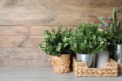 Photo of Different artificial potted herbs on white wooden table, space for text