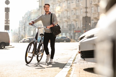 Photo of Handsome happy man with bicycle on city street