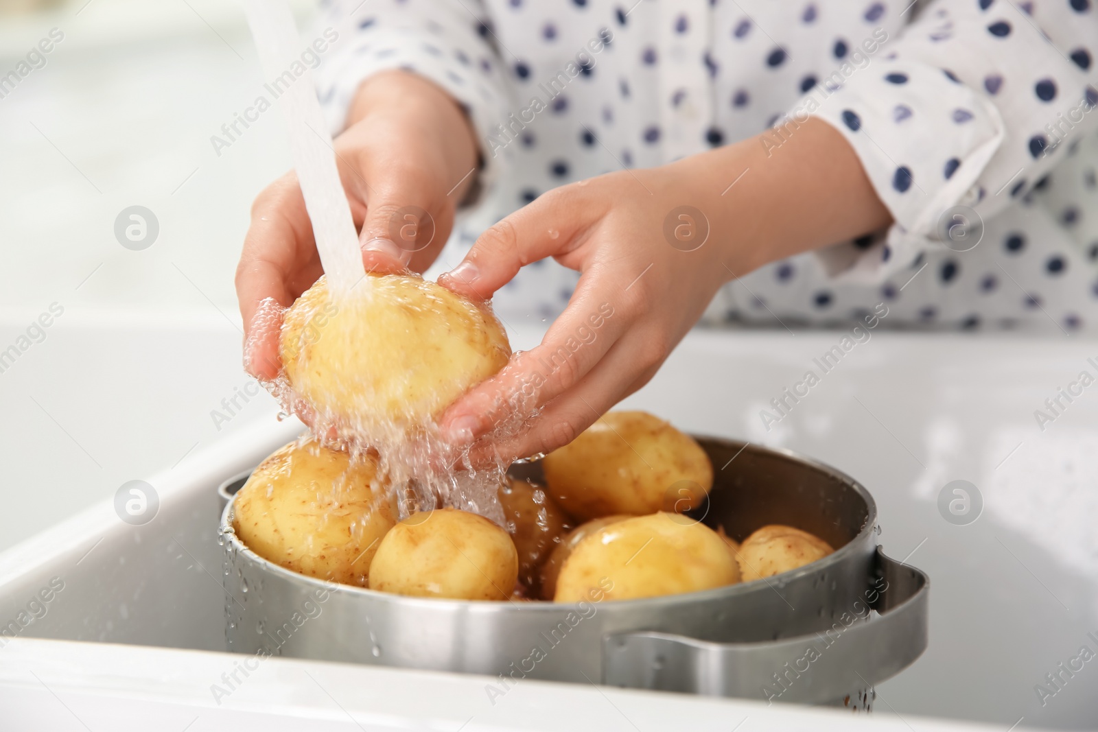 Photo of Woman washing fresh potatoes in kitchen sink, closeup