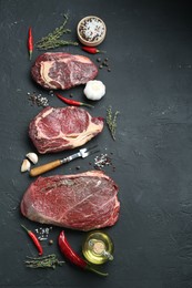 Photo of Pieces of raw beef meat, products and spices on black textured table, flat lay. Space for text