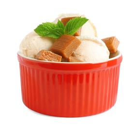 Photo of Bowl of delicious ice cream with caramel candies and mint on white background