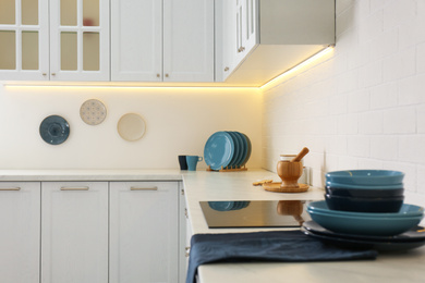 Photo of Stylish kitchen interior with modern cooktop and white furniture