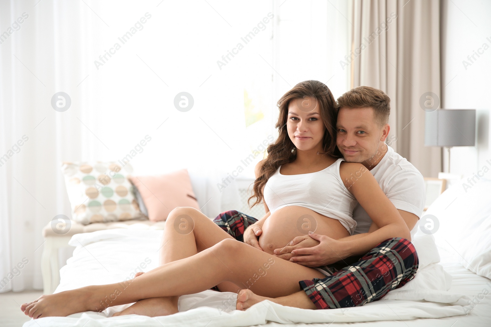 Photo of Pregnant woman with her husband in bedroom. Space for text