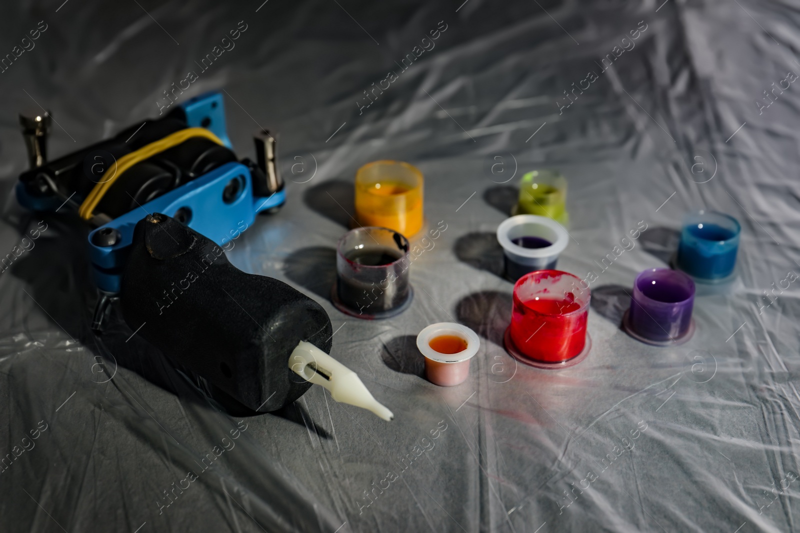 Photo of Caps with colorful inks and tattoo machine on table