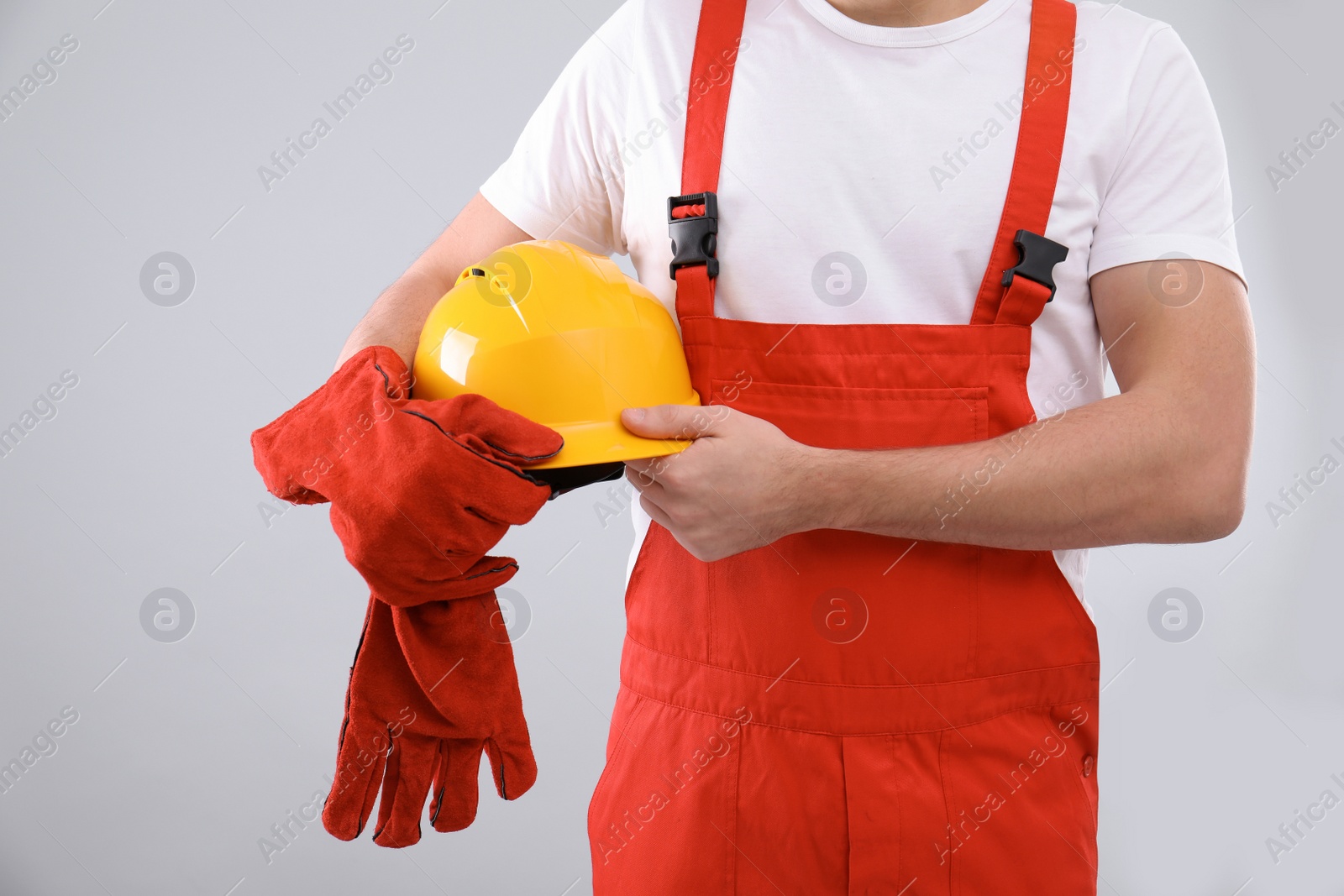 Photo of Male industrial worker in uniform on light background, closeup. Safety equipment