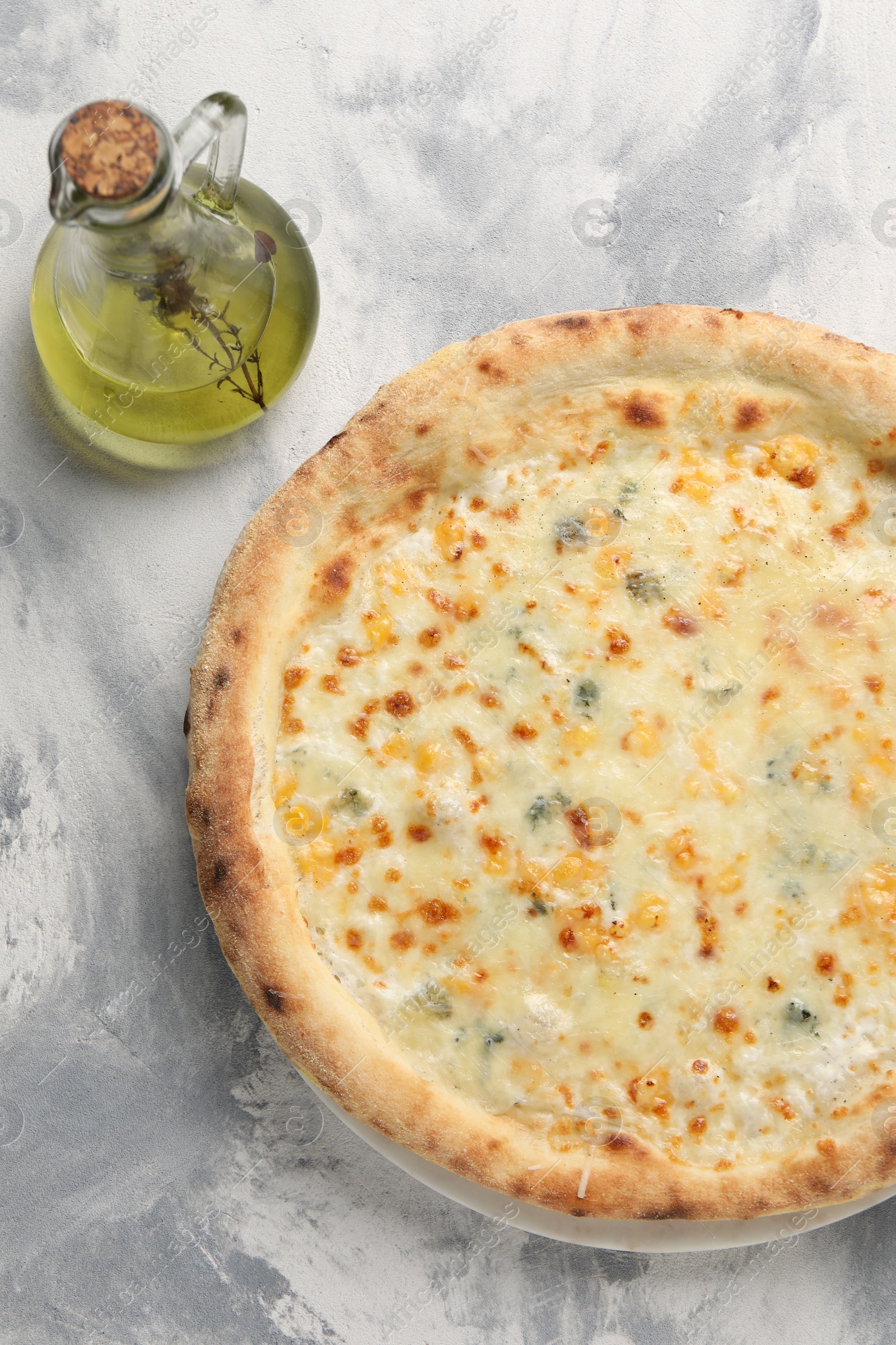 Photo of Delicious cheese pizza and oil on light grey textured table, flat lay