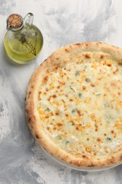 Delicious cheese pizza and oil on light grey textured table, flat lay