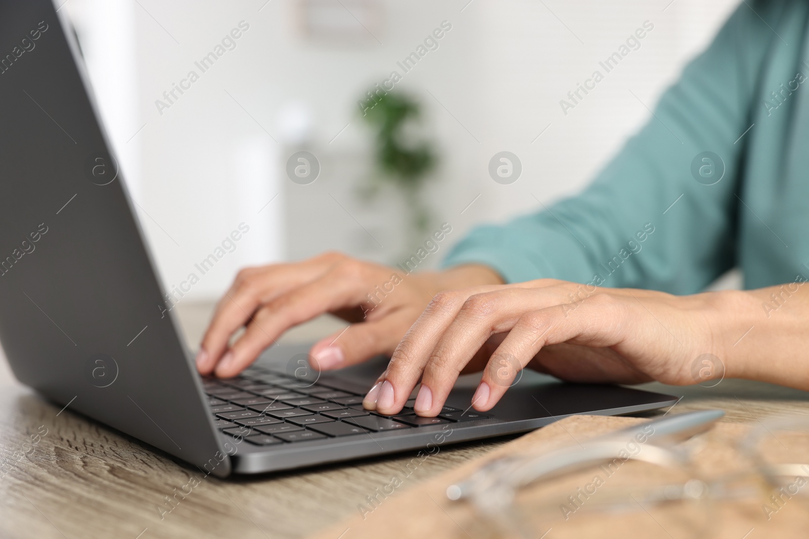 Photo of Woman using laptop at wooden desk indoors, closeup