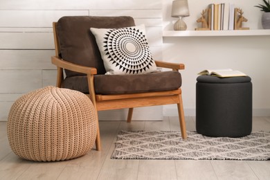 Stylish comfortable poufs near armchair in room. Home design