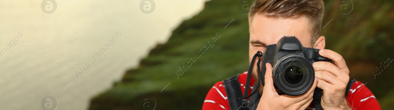 Image of Male photographer taking picture with professional camera outdoors, space for text. Banner design