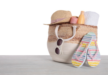 Bag with beach objects on table against white background. Space for text