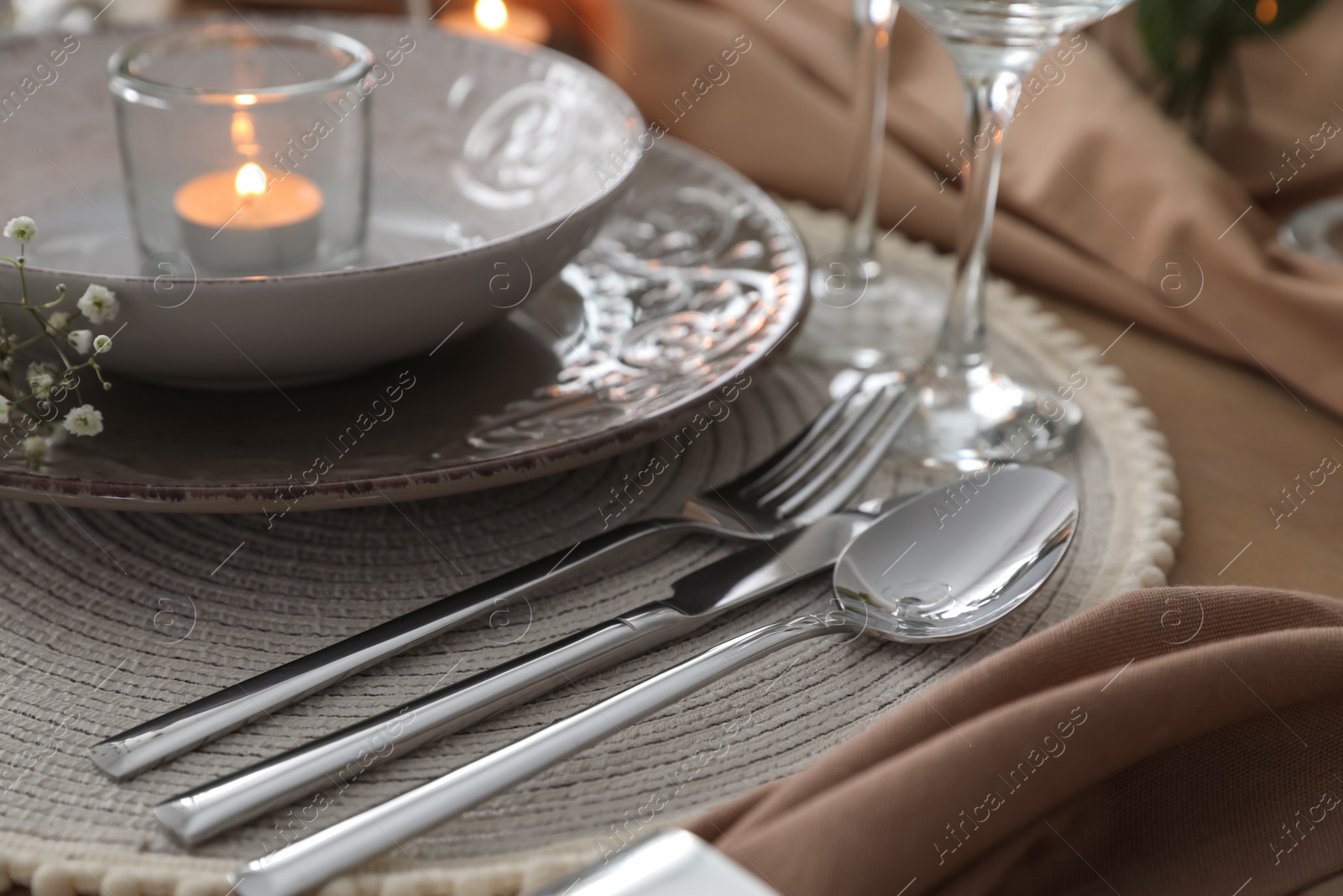 Photo of Festive table setting with beautiful candle and floral decor, closeup