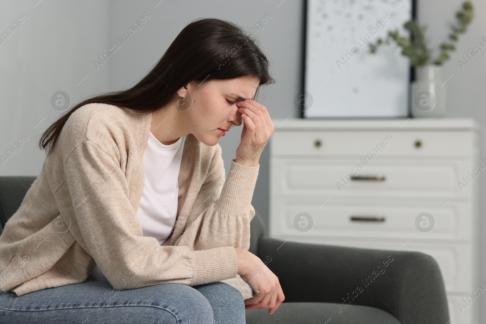 Photo of Overwhelmed woman sitting on sofa at home