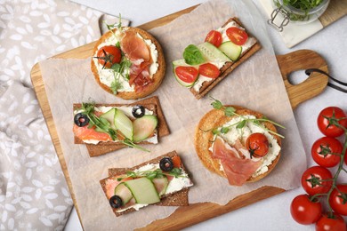 Photo of Tasty rusks and rye crispbreads with different toppings on light grey table, flat lay