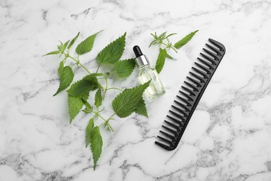Photo of Stinging nettle, extract and comb on white marble background, flat lay. Natural hair care