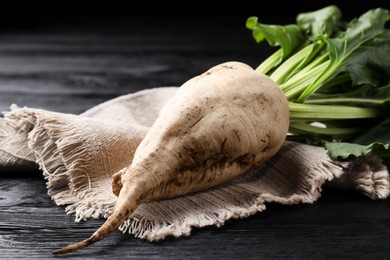 Fresh sugar beet with leaves on black wooden table, closeup