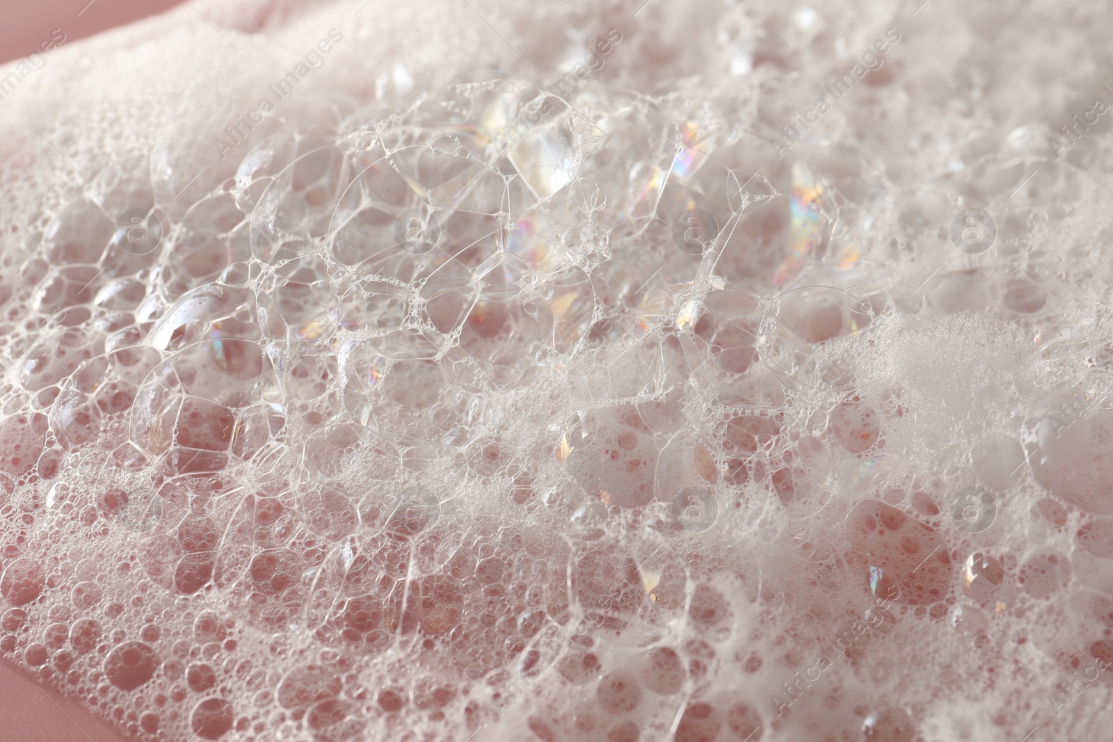 Photo of White washing foam on pale pink background, closeup