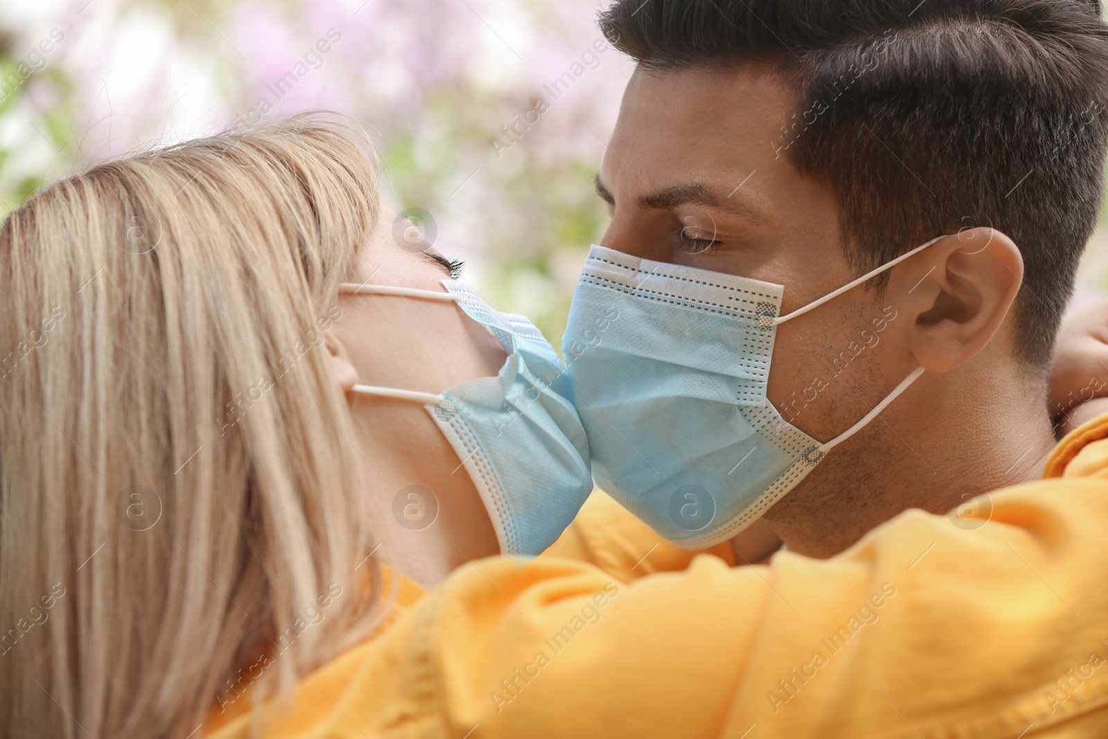 Photo of Couple in medical masks trying to kiss outdoors