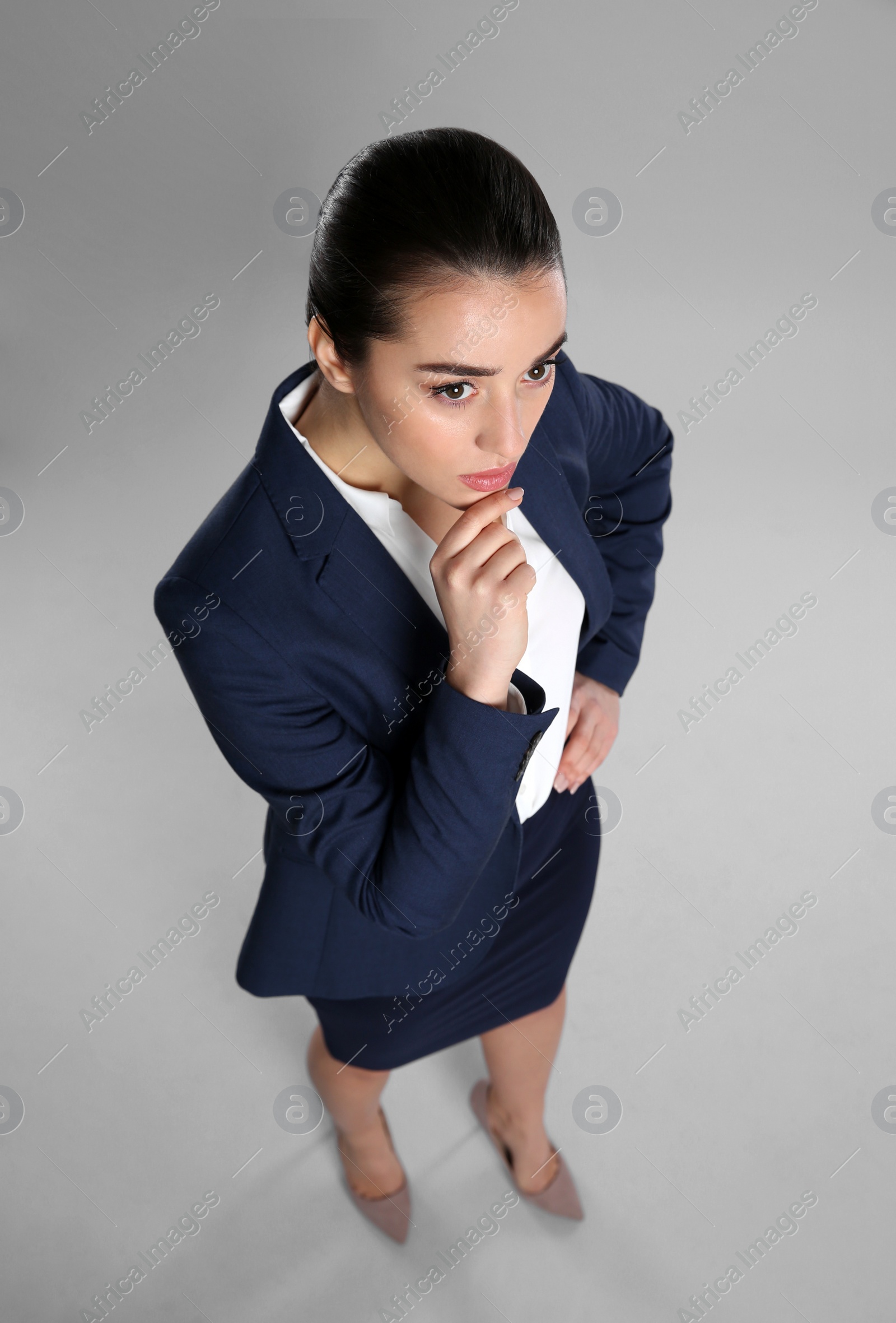 Photo of Young thoughtful businesswoman in elegant suit on grey background, above view
