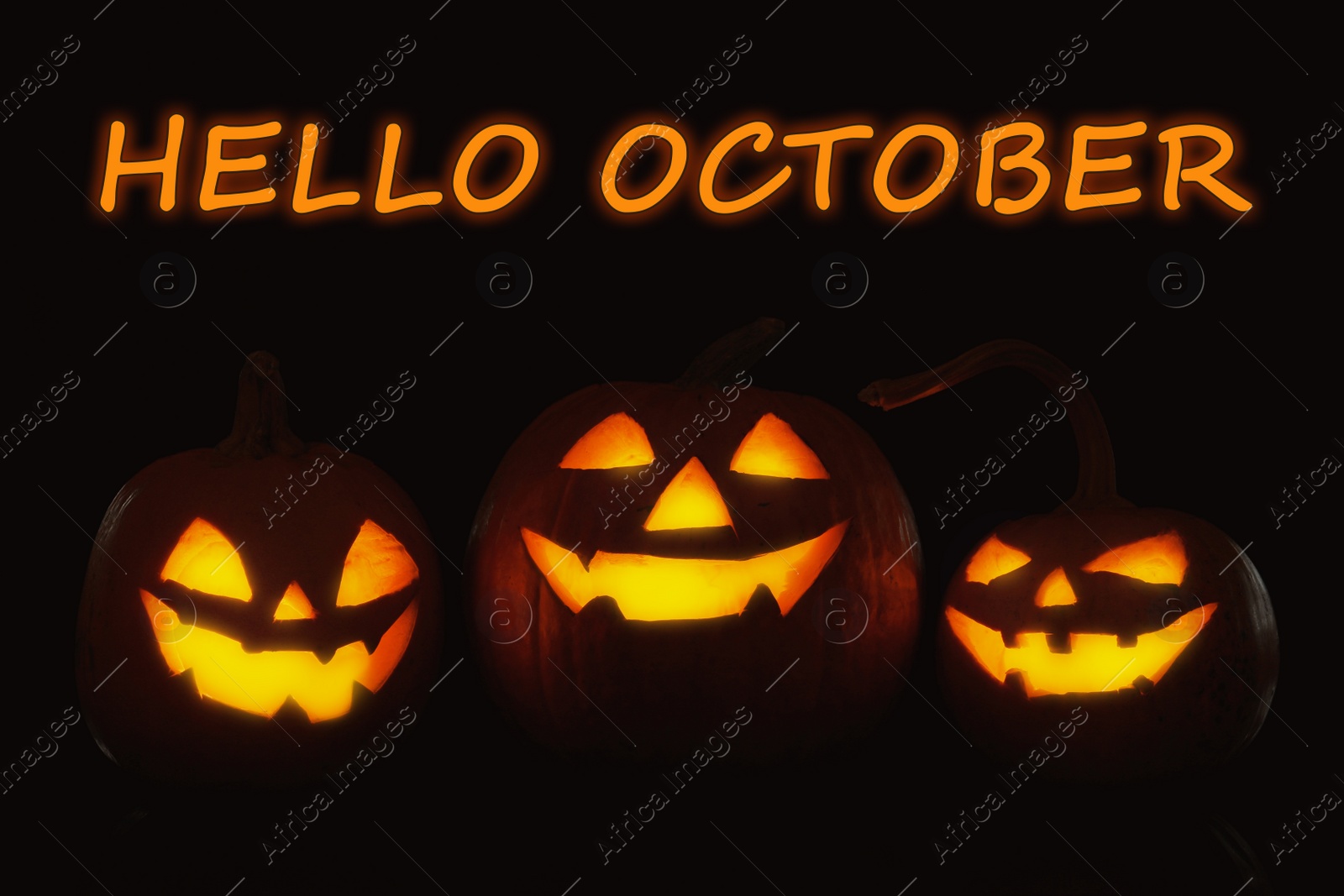 Image of Hello October card. Halloween pumpkin heads glowing in darkness