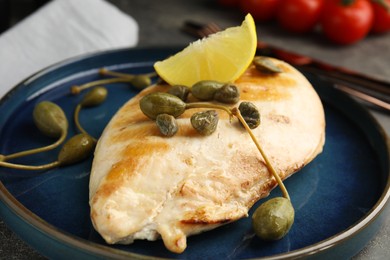 Photo of Delicious cooked chicken fillet with capers and lemon slice on plate, closeup