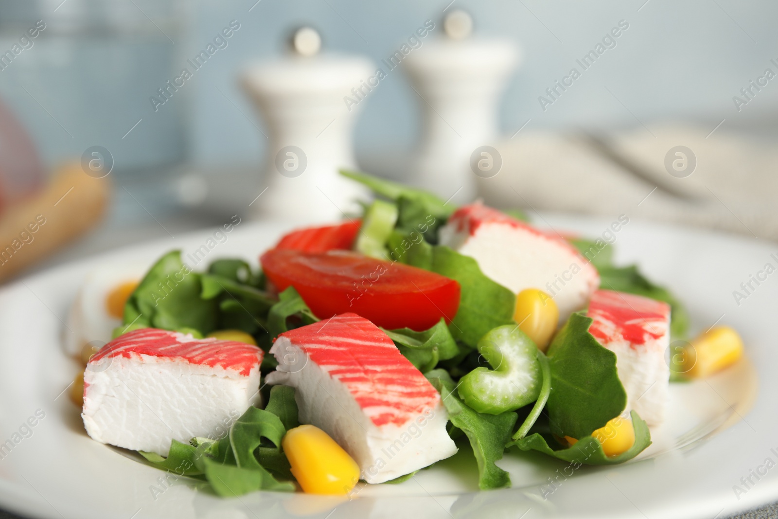 Photo of Delicious crab stick salad on white plate, closeup