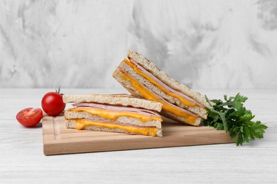 Photo of Delicious grilled sandwiches with ham, cheese and products on white wooden table