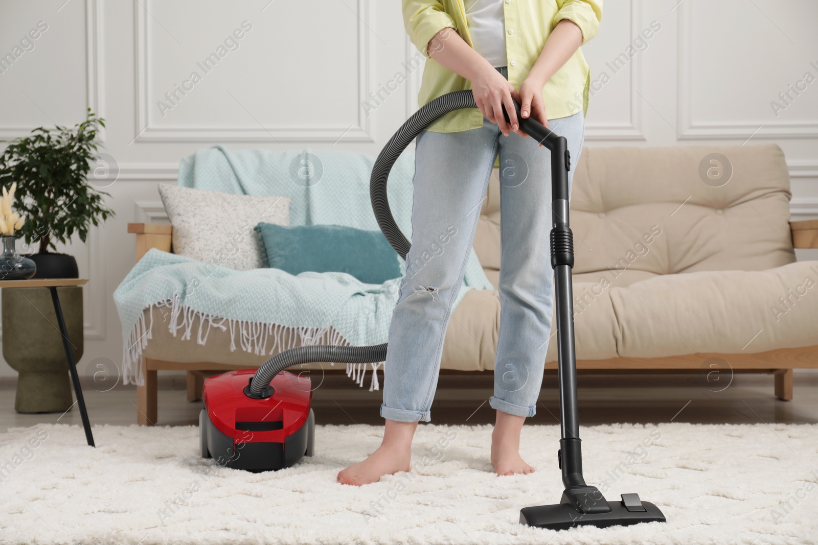 Photo of Woman cleaning carpet with vacuum cleaner at home, closeup