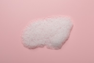 Photo of Drop of fluffy soap foam on pink background, top view