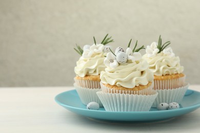 Tasty Easter cupcakes with vanilla cream on light wooden table, space for text