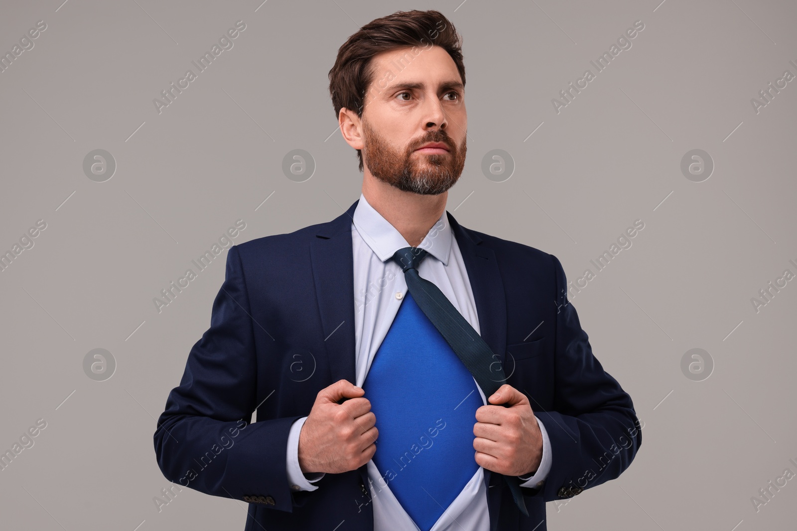 Photo of Confident businessman wearing superhero costume under suit on beige background