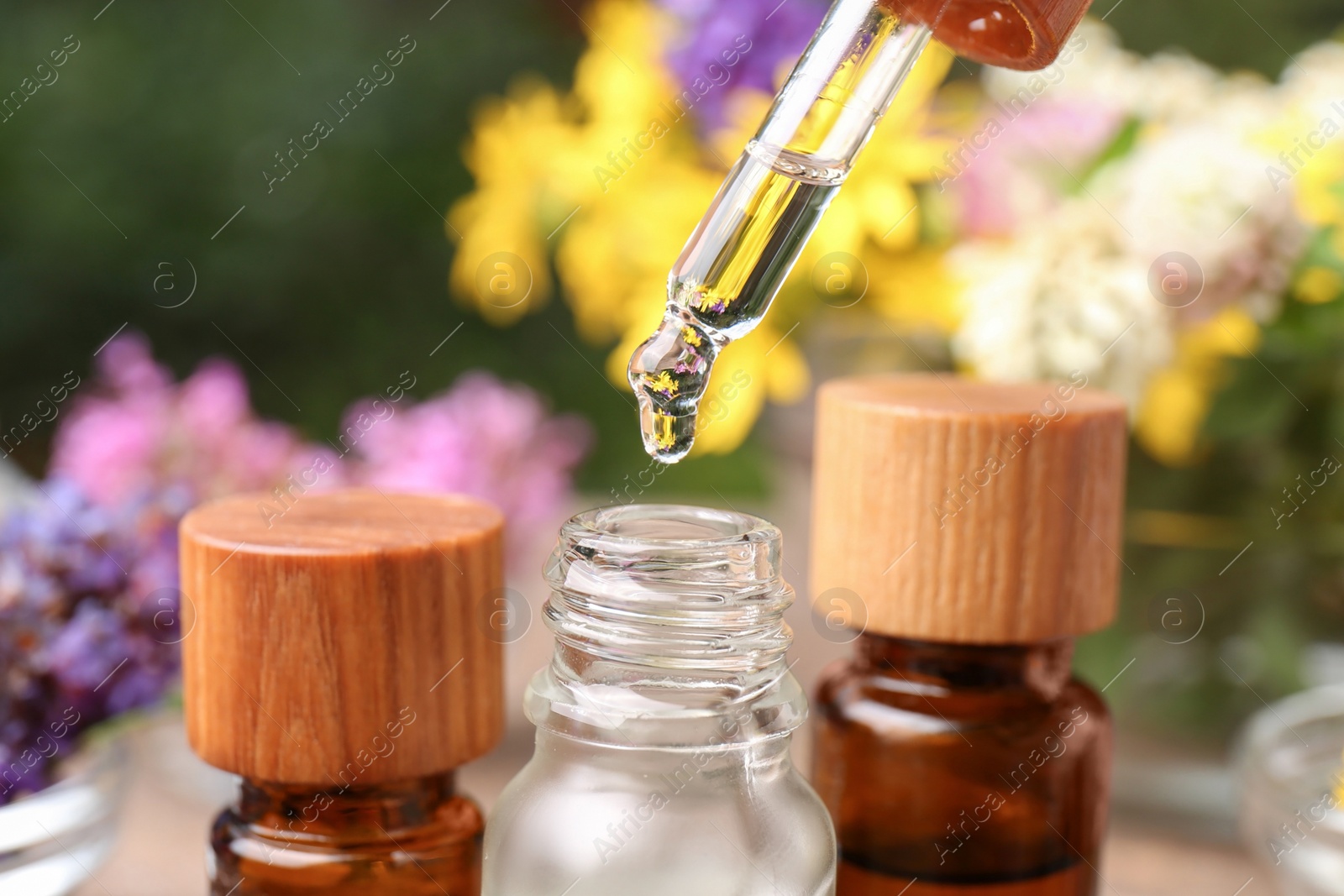 Photo of Dripping essential oil from pipette into bottle, closeup