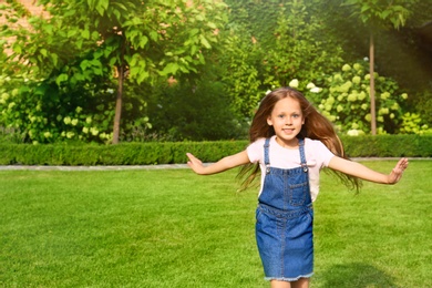 Photo of Cute little girl running in green park on summer day