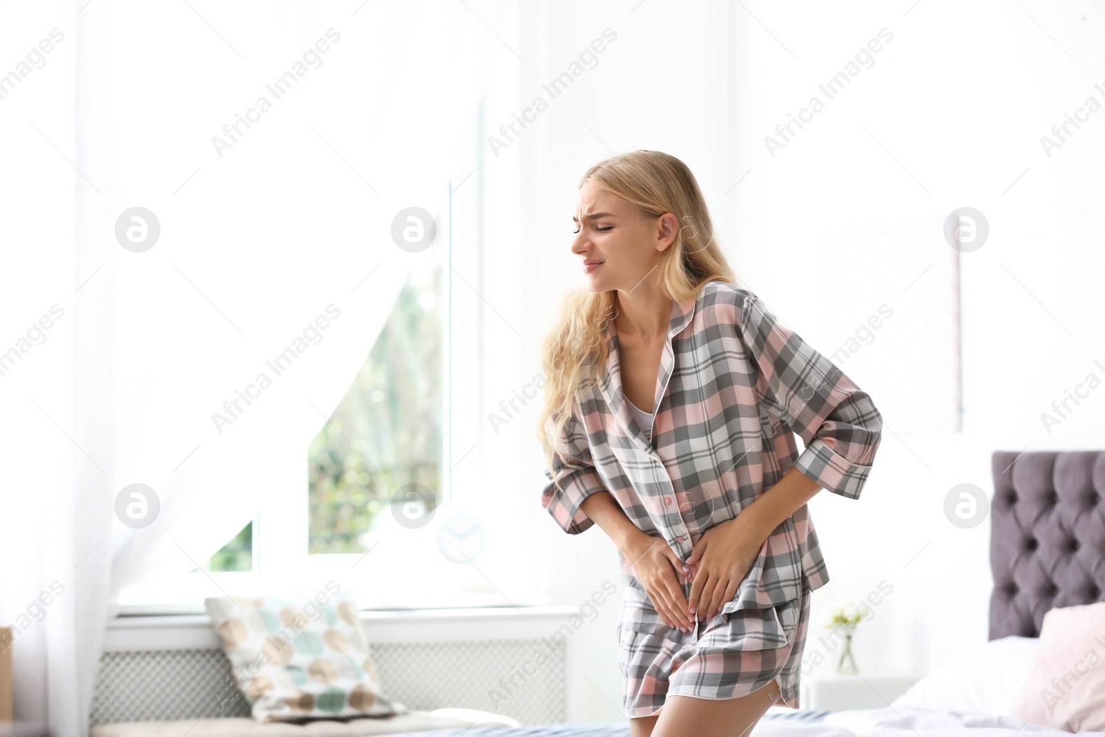 Photo of Young woman suffering from pain in bedroom. Gynecology concept