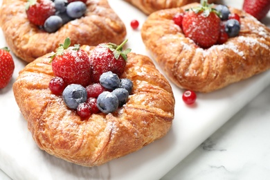 Fresh delicious puff pastry with sweet berries on white marble board, closeup