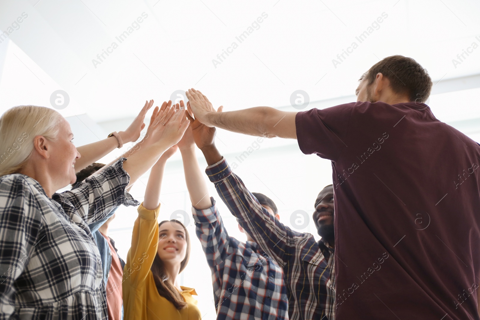 Photo of People putting hands together indoors. Unity concept