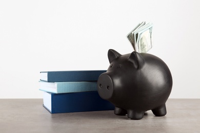 Piggy bank with dollars and books on table against white background