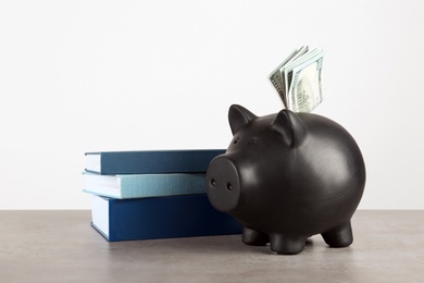 Photo of Piggy bank with dollars and books on table against white background