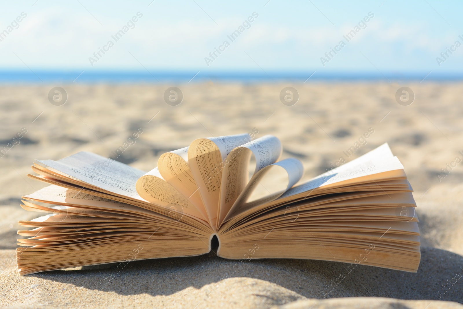 Photo of Open book on sandy beach near sea