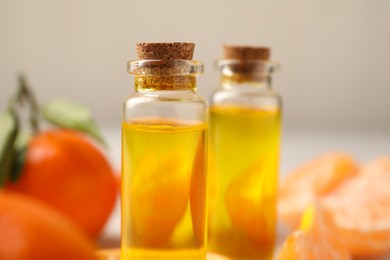 Photo of Bottles of tangerine essential oil on blurred background, closeup