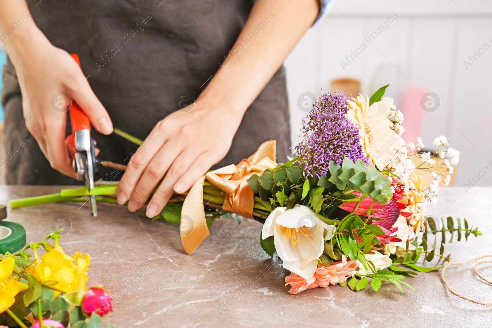 Photo of Female florist pruning stem at table