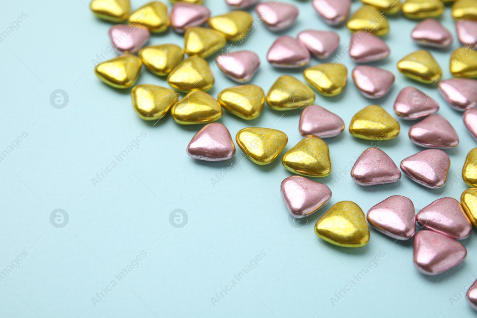 Photo of Many delicious heart shaped candies on light blue background. Space for text