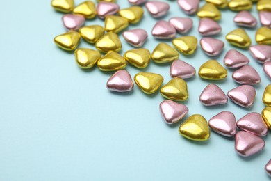 Photo of Many delicious heart shaped candies on light blue background. Space for text