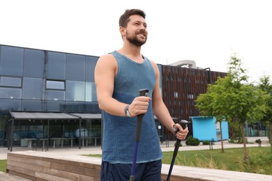 Photo of Man practicing Nordic walking with poles outdoors, low angle view