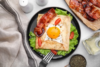 Photo of Delicious crepe with egg served on light gray table, flat lay. Breton galette
