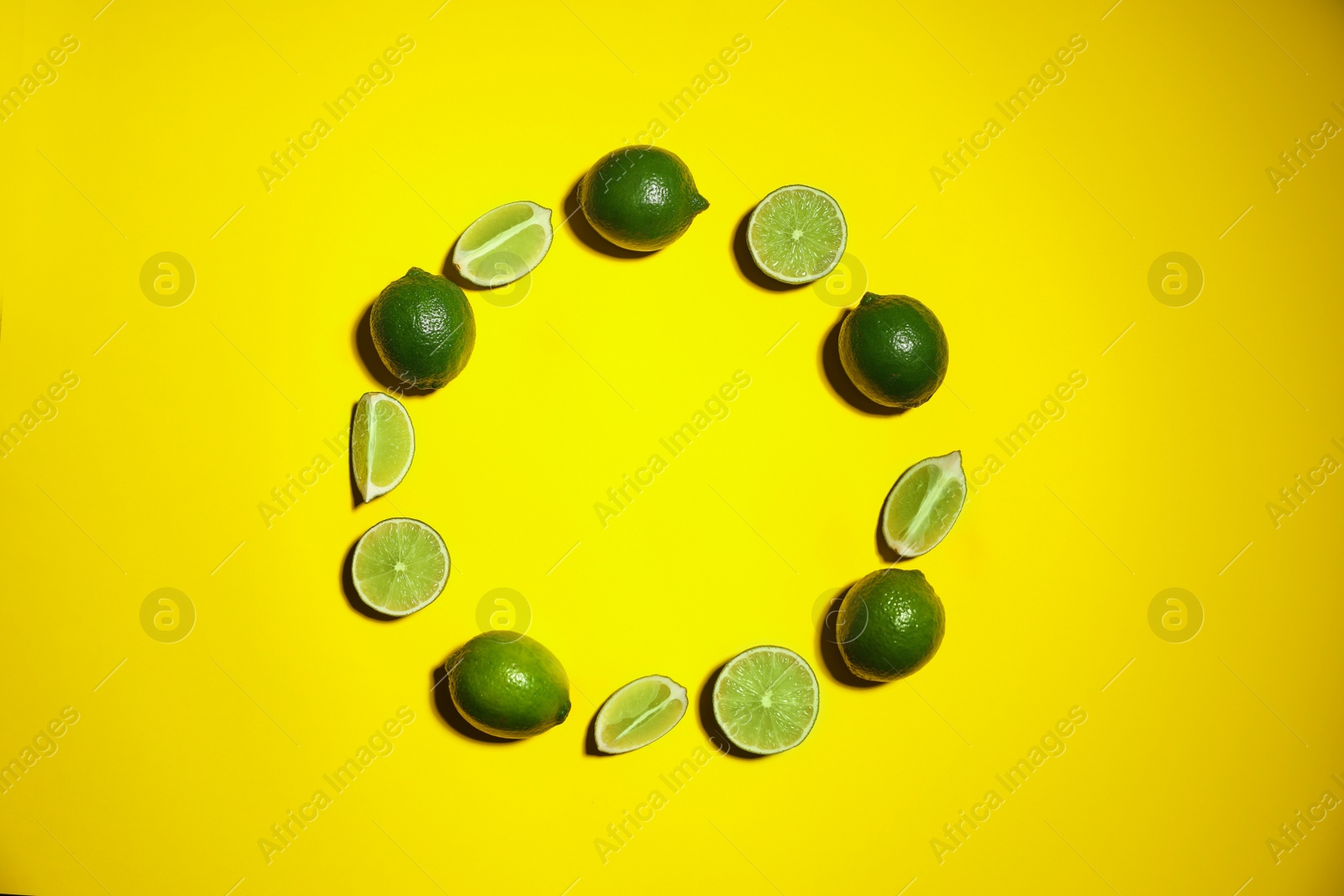 Photo of Flat lay composition with fresh juicy limes on yellow background. Space for text