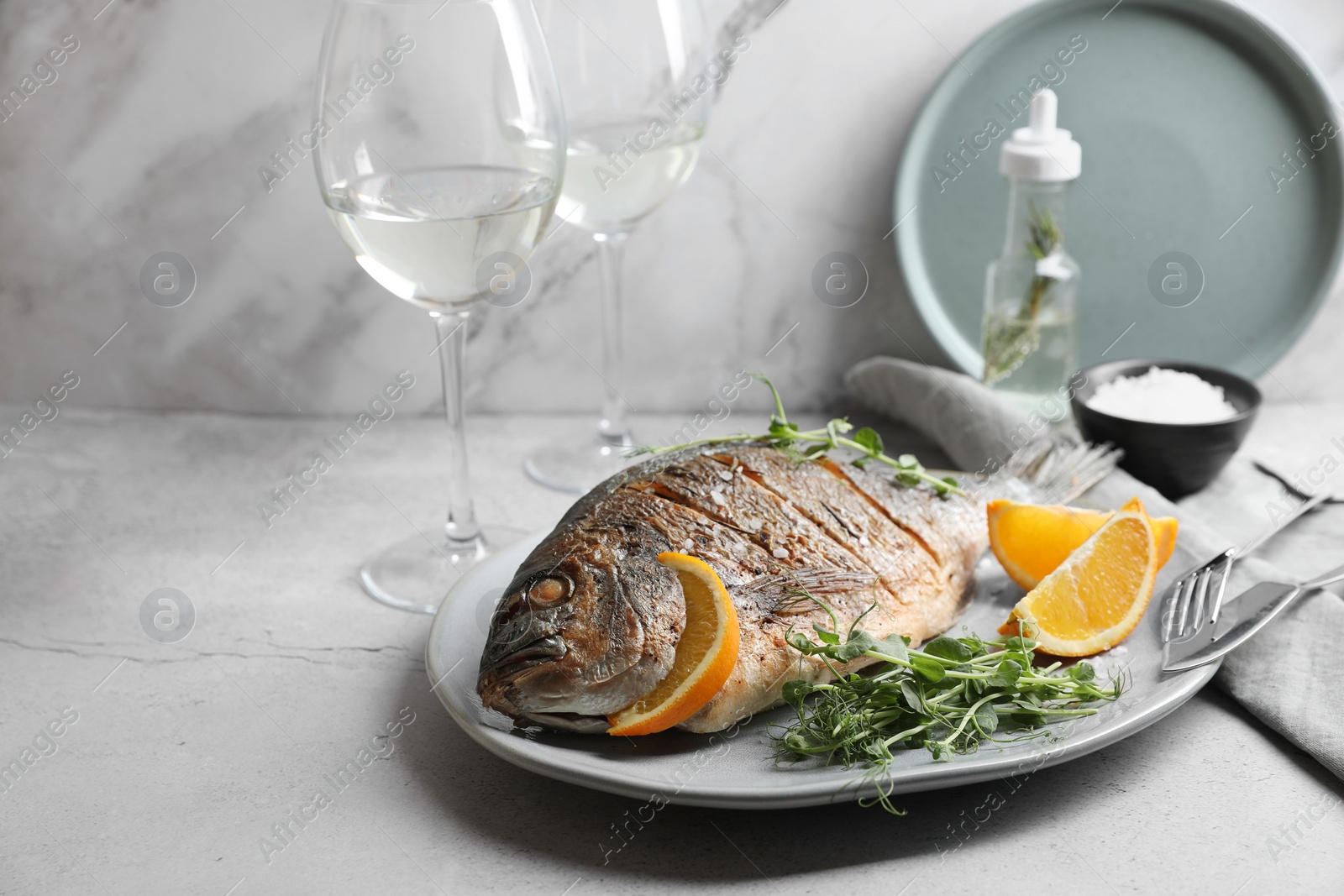 Photo of Seafood. Delicious baked fish served with orange and microgreens on light textured table, space for text
