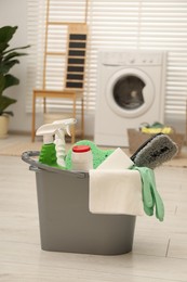 Photo of Different cleaning products in bucket on floor indoors